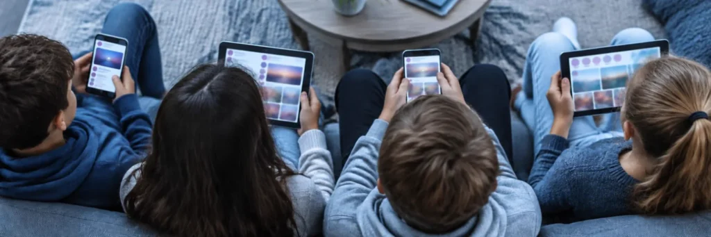 Vier junge Menschen auf einem Sofa schauen auf Smartphones und Tablets mit Social-Media-Inhalten.